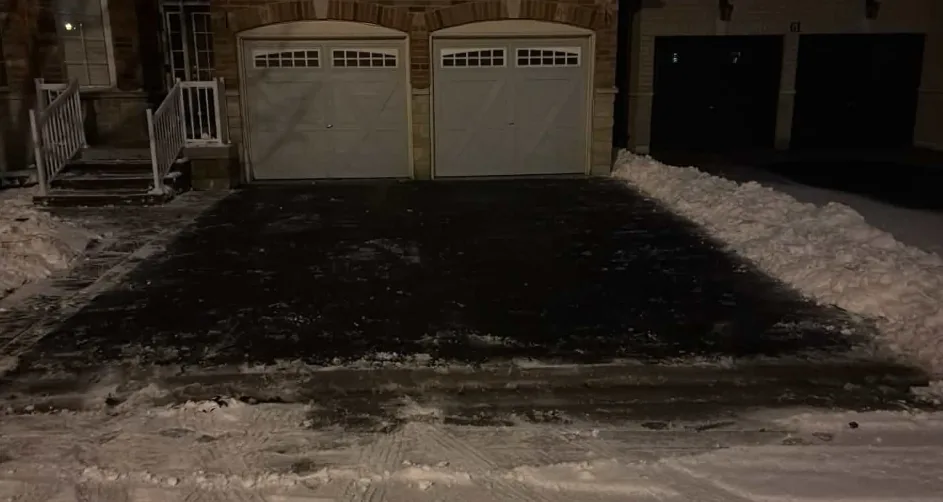 Double driveway cleared of snow in front of a brick home at night in Toronto, Ontario