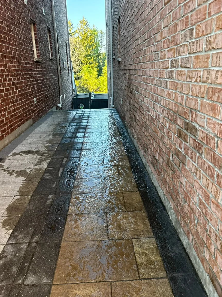 Interlocking paver walkway with dark border stones between two brick houses in Ajax, Ontario