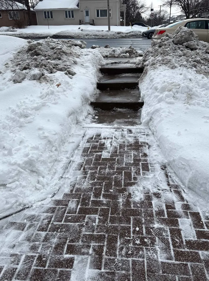 Brick walkway and front steps cleared of snow between snow banks in Durham Region, Ontario