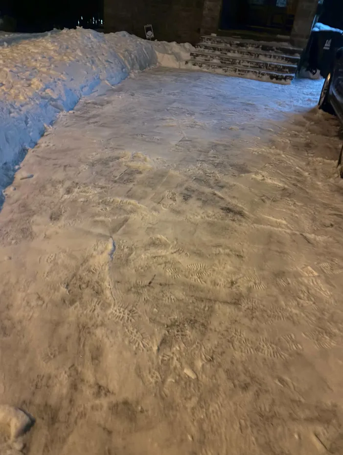 Residential driveway cleared of snow at night with snow banks on either side in Durham Region, Ontario