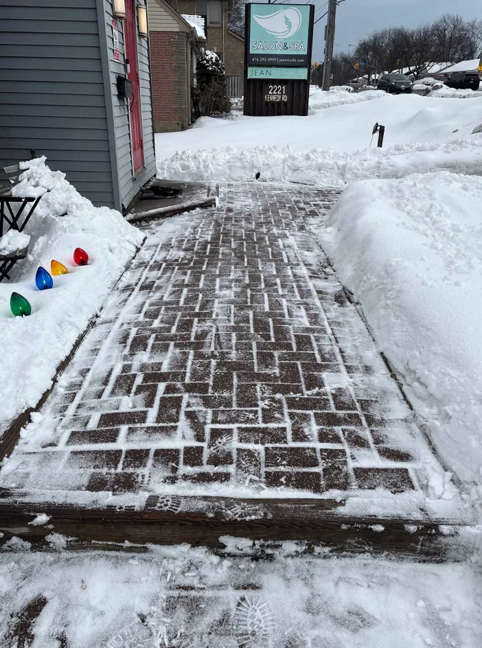 Snow cleared from a brick walkway beside a home, with snow piled along the edges in Durham Region, Ontario