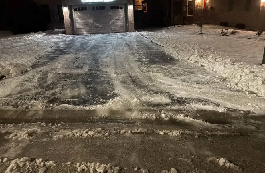 Wide driveway cleared of snow in front of a garage at night in Durham Region, Ontario